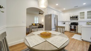 A modern kitchen with white cabinets, stainless steel appliances, and a round dining table with placemats. - Cocktail Pool! Fredericksburg Bungalow By Main St (Fredericksburg)