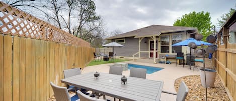A backyard with a pool, outdoor furniture, and a covered patio area.