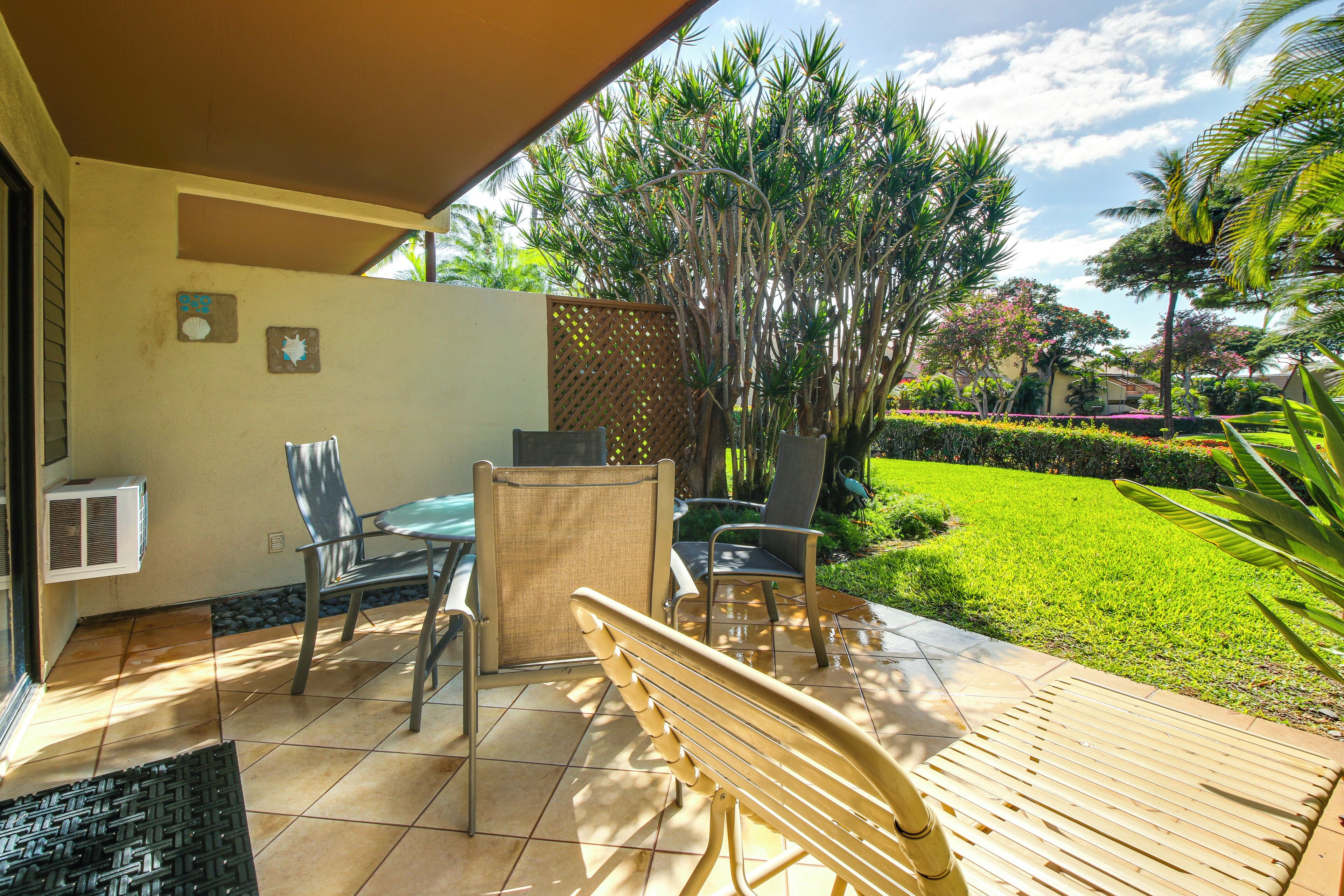 An outdoor patio with a wooden bench, two chairs, and a table.