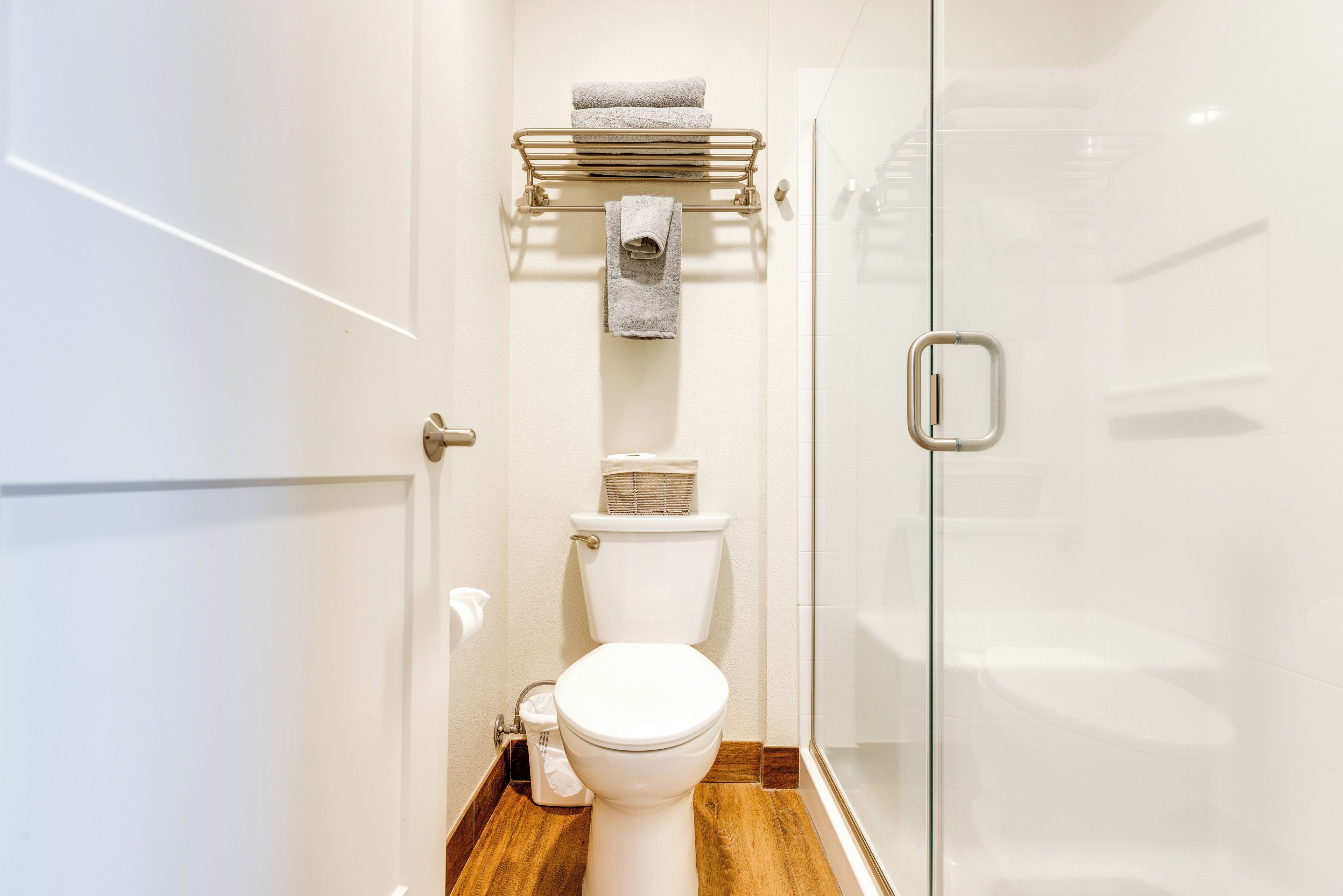 Ein modernes Badezimmer mit Toilette, Handtuchhalter und einer Duschkabine aus Glas.