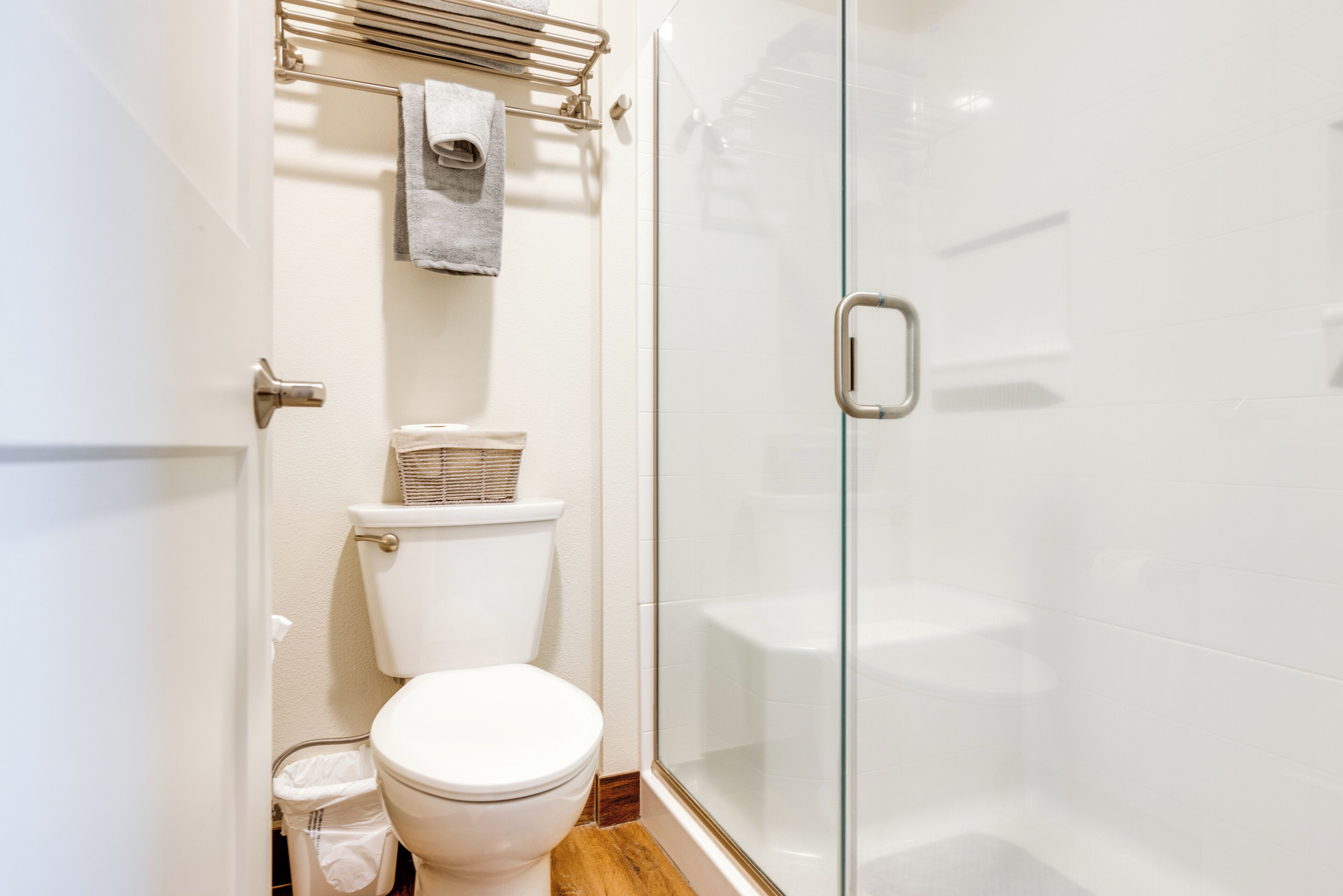 A modern bathroom with a toilet, a glass shower enclosure, and a towel rack.