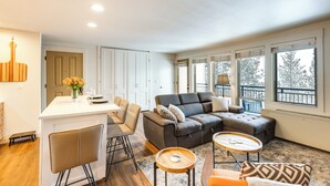 Een moderne woonkamer met een bank, salontafel en een eethoek.