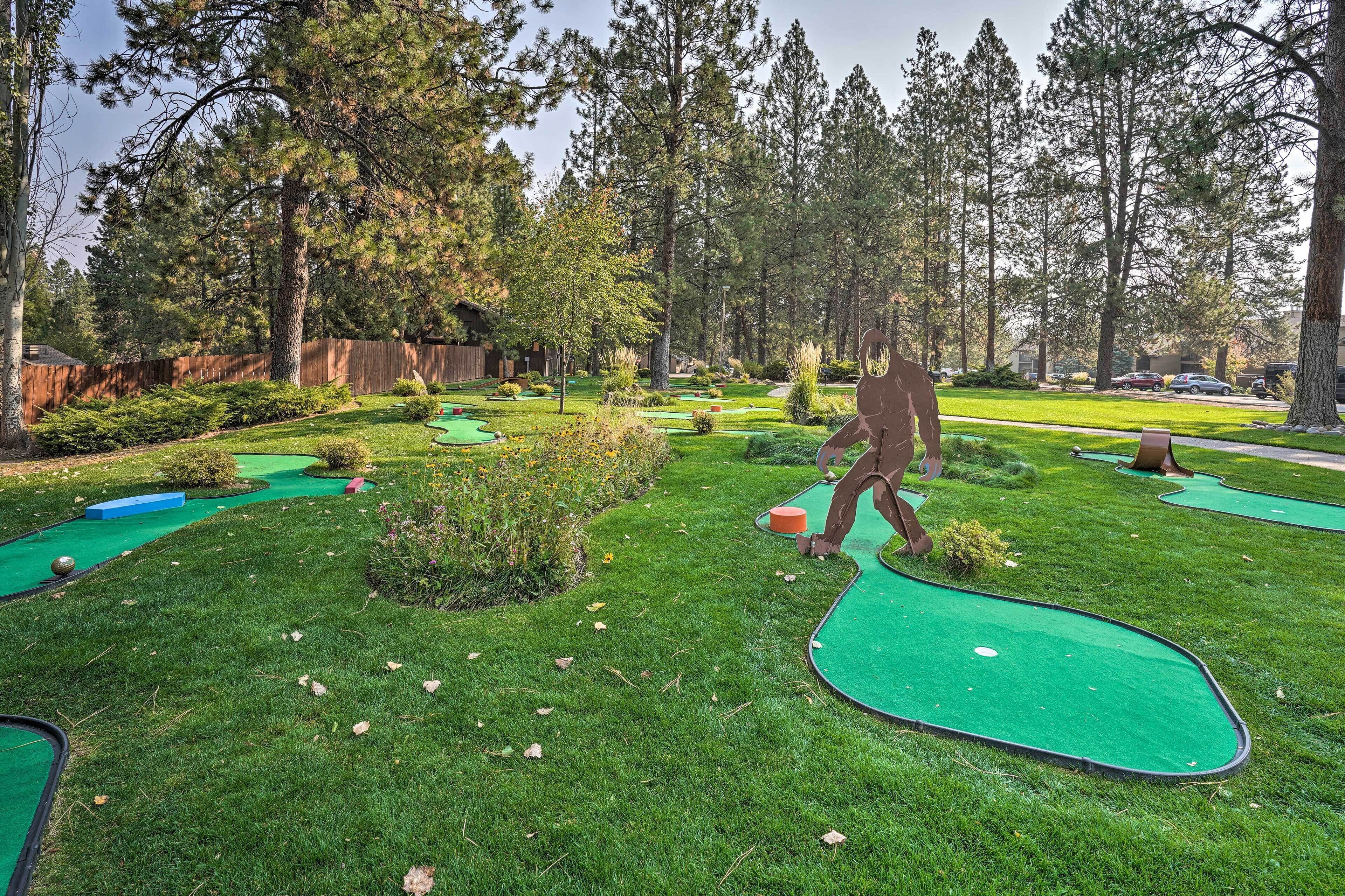 Un campo de minigolf con una escultura de madera de una persona en posición de golf.
