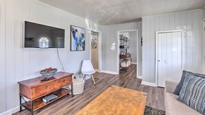 A living room with a wooden coffee table, a white sofa, a TV mounted on the wall, and a wooden cabinet. - Tuscaloosa House 2 Mi to Coleman Coliseum! (Tuscaloosa)