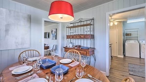 A dining area with a wooden table set for six, a red hanging light, and a metal rack with glasses. - Tuscaloosa House 2 Mi to Coleman Coliseum! (Tuscaloosa)