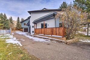 A modern two-story house with a covered porch, a wooden fence, and a driveway.