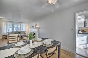 A dining area with a dark wooden table set for four, surrounded by wicker chairs, and a white ceiling fan above. - Cozy West Sacramento Getaway w/ Private Yard! (West Sacramento)