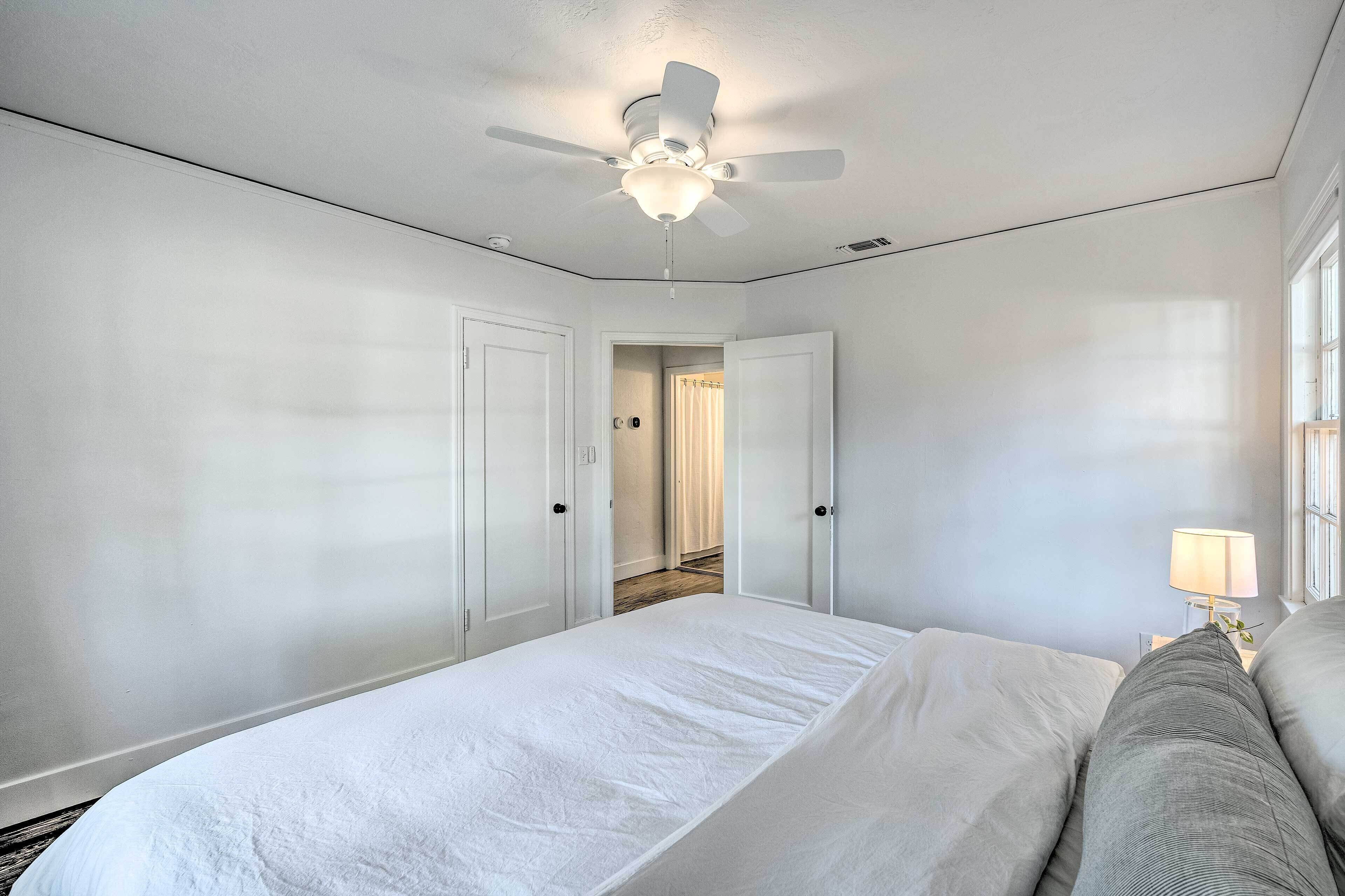 Un dormitorio con cama, ventilador de techo y mesita de noche con lámpara.