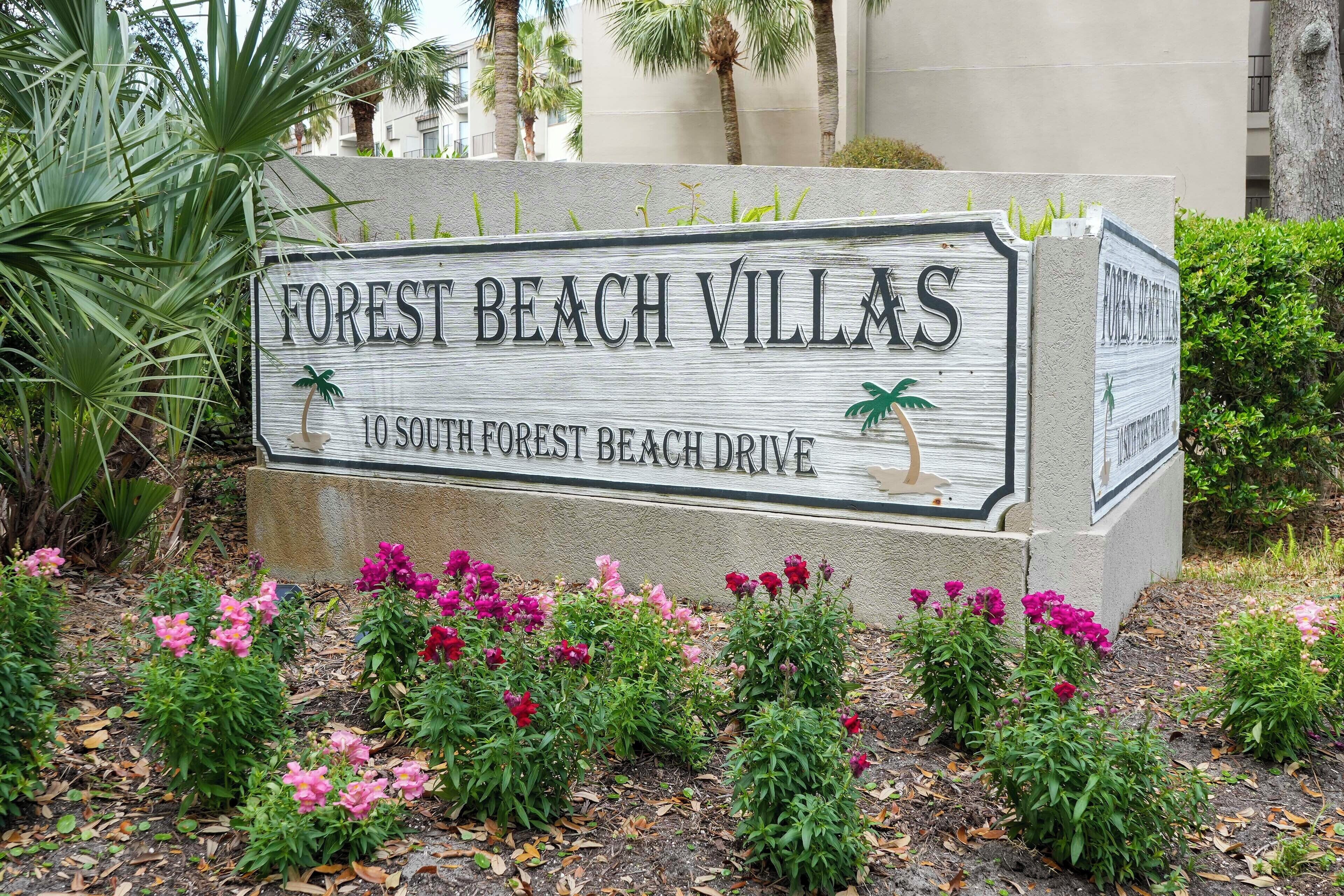 Une enseigne pour le complexe Forest Beach Villas, avec une illustration d’un palmier et d’un oiseau.