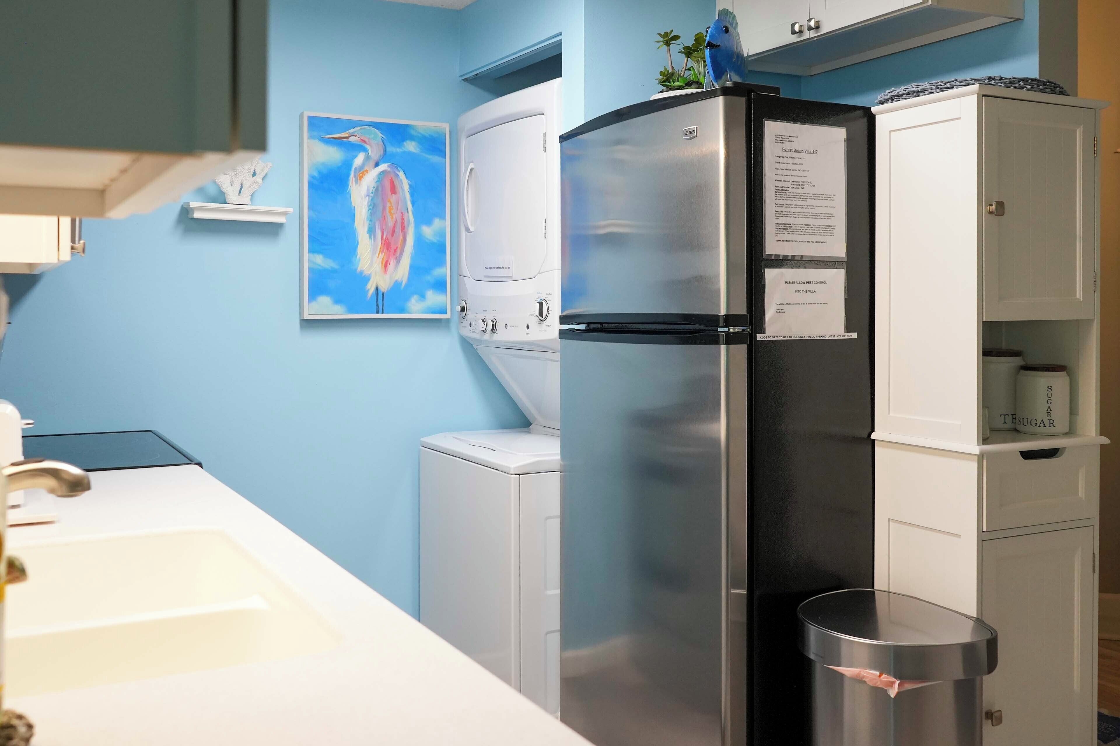 A kitchen with a stainless steel refrigerator, a washing machine, and a sink.