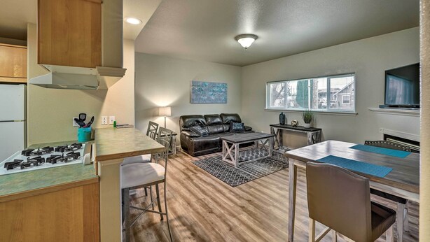 A compact kitchen with a gas stove, wooden cabinets, and a dining area with a table and chairs. - Central Apt: Private Fireplace & Patio Access (Anacortes)