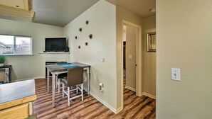 A compact living space with a dining area, a TV mounted on the wall, and a staircase leading to another level. - Central Apt: Private Fireplace & Patio Access (Anacortes)