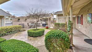A covered patio area with a barbecue grill, outdoor seating, and neatly trimmed bushes. - Central Apt: Private Fireplace & Patio Access (Anacortes)