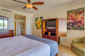 Ein Schlafzimmer mit einem Bett, einem Holz-Fernsehschrank, einem Deckenventilator und Kunstwerken an den Wänden.