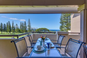 Ein Balkon mit Tisch für Zwei, mit Blick auf einen Golfplatz und das Meer.