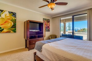 Ein Schlafzimmer mit Bett, Fernseher, Deckenventilator, großem Fenster und Blick ins Freie.