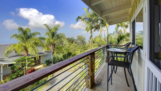 A balcony with a wooden railing, a table, and two chairs. - Charming Kailua-kona Apartment Near Hiking & Golf! (Kailua-Kona)