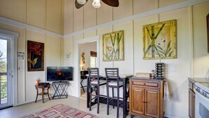A dining area with a TV, wooden chairs, a table, and a cabinet. - Charming Kailua-kona Apartment Near Hiking & Golf! (Kailua-Kona)