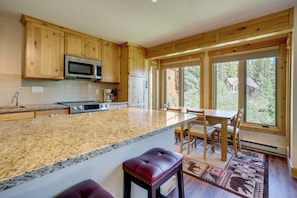 A kitchen with wooden cabinets, a granite countertop, a microwave, and a refrigerator. - Ski-in Breck Condo: Walk to Shops & Restaurants! (Breckenridge)