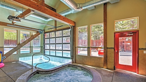 A hot tub area with a wooden ceiling, large windows, and a red door. - Ski-in Breck Condo: Walk to Shops & Restaurants! (Breckenridge)