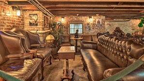 A cozy room with leather sofas, a small table, and a brick wall with posters.