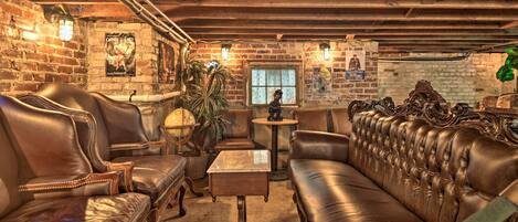 A cozy room with leather sofas, a small table, and a brick wall with posters.