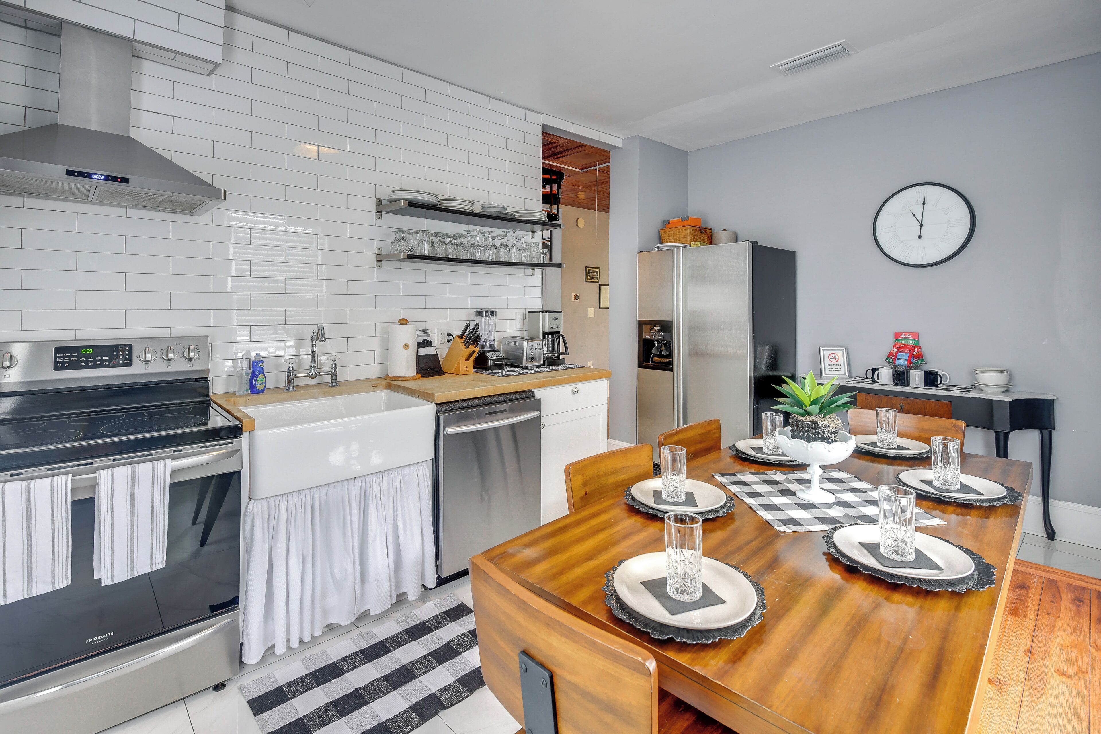Une cuisine moderne avec des carreaux de métro blancs, des appareils en acier inoxydable et une table à manger en bois pour quatre personnes.