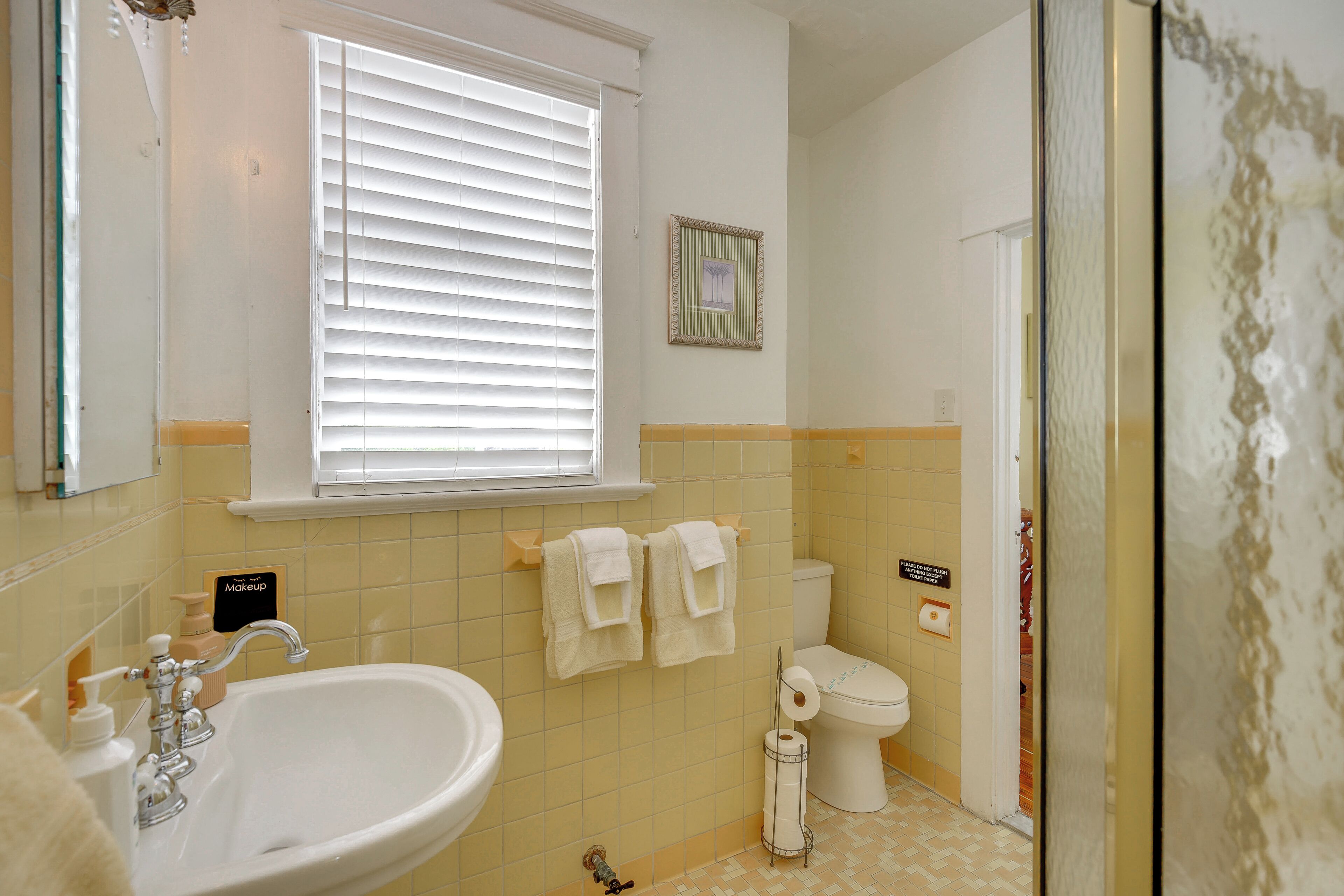 Une salle de bain avec un lavabo, des toilettes et une fenêtre.
