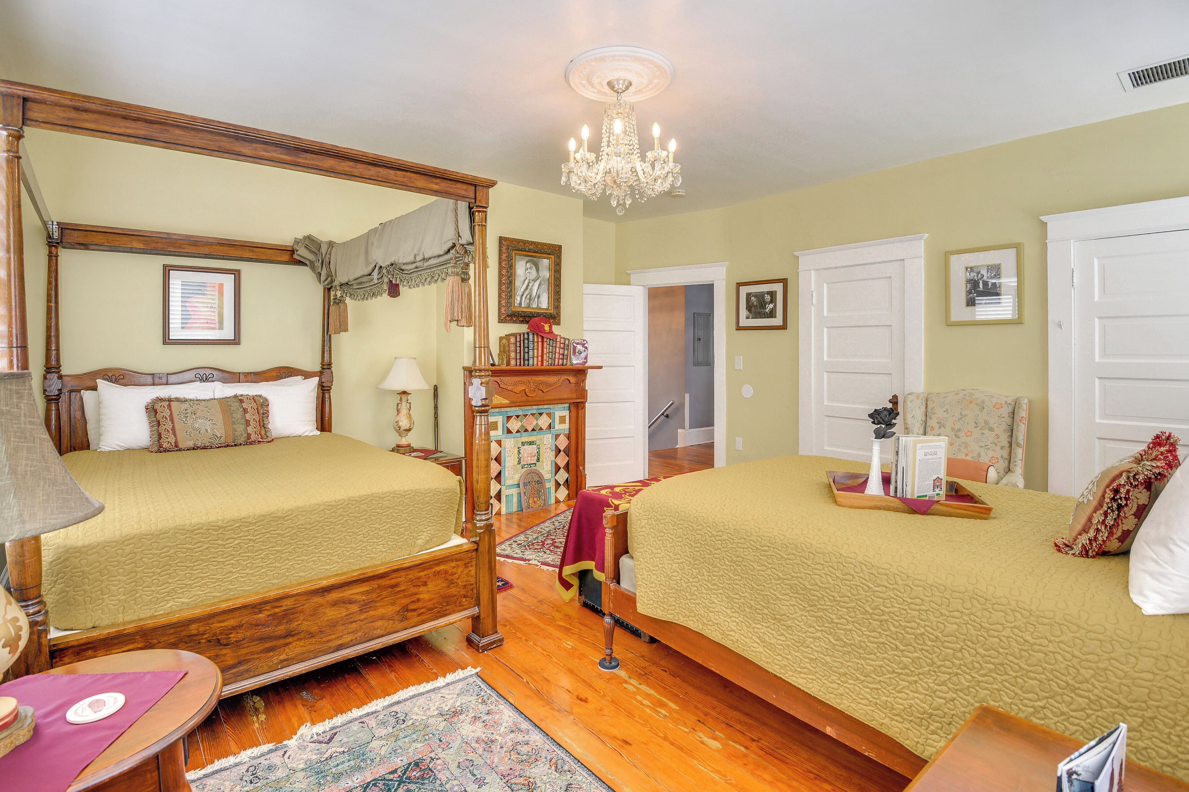 Une chambre à coucher de style traditionnel, avec deux lits, un lustre et un plancher en bois.