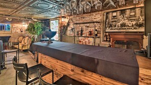 A bar area with a long counter, hanging wine glasses, and a vintage poster on the wall.