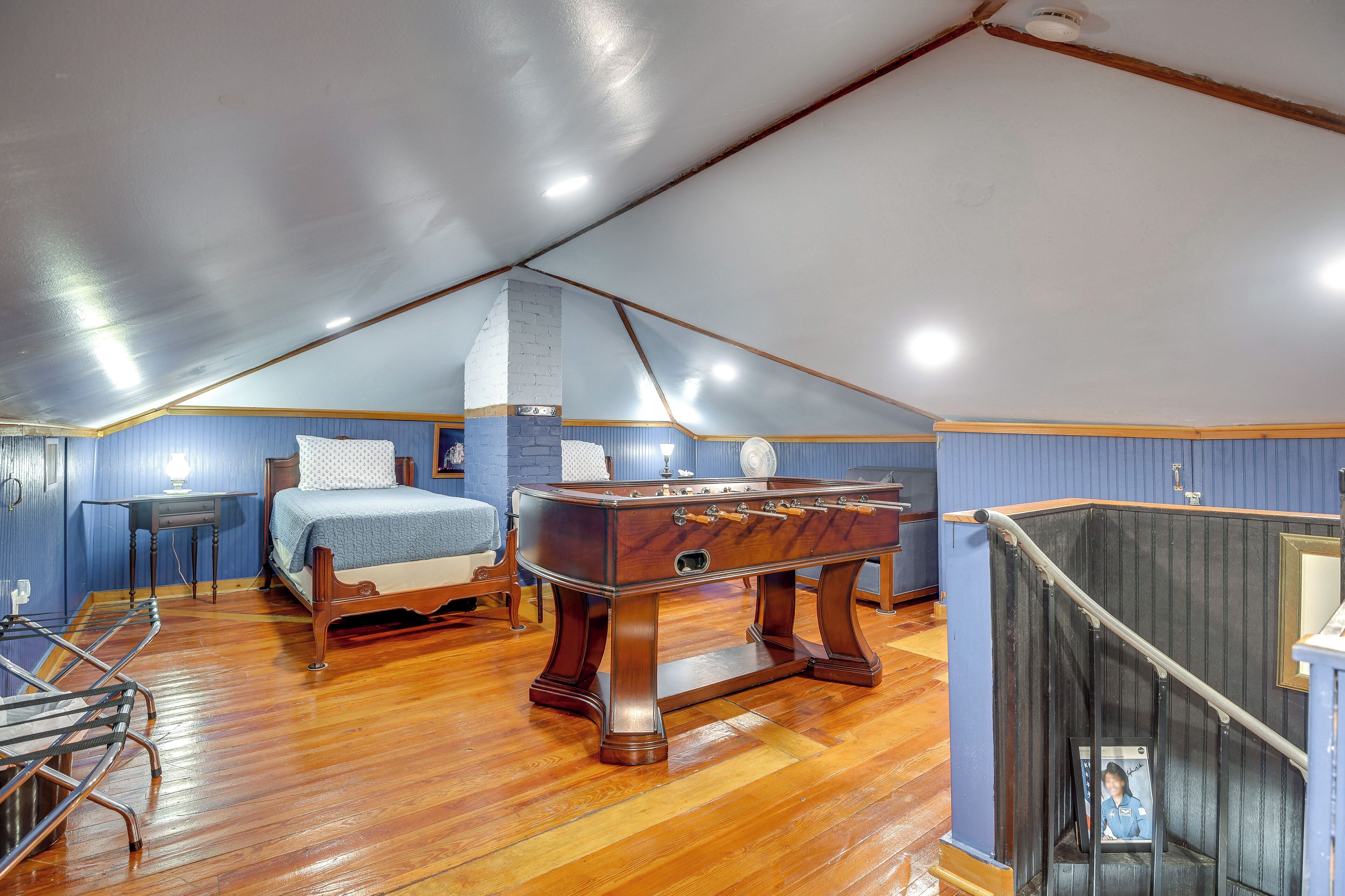 Een slaapkamer met een houten bed, een houten pooltafel, een blauwe muur en een houten trap.