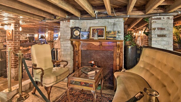 A cozy room with a brick fireplace, leather chairs, and a wooden coffee table.