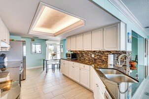 Una cocina moderna con armarios blancos, salpicadero de azulejos y pileta de acero inoxidable.