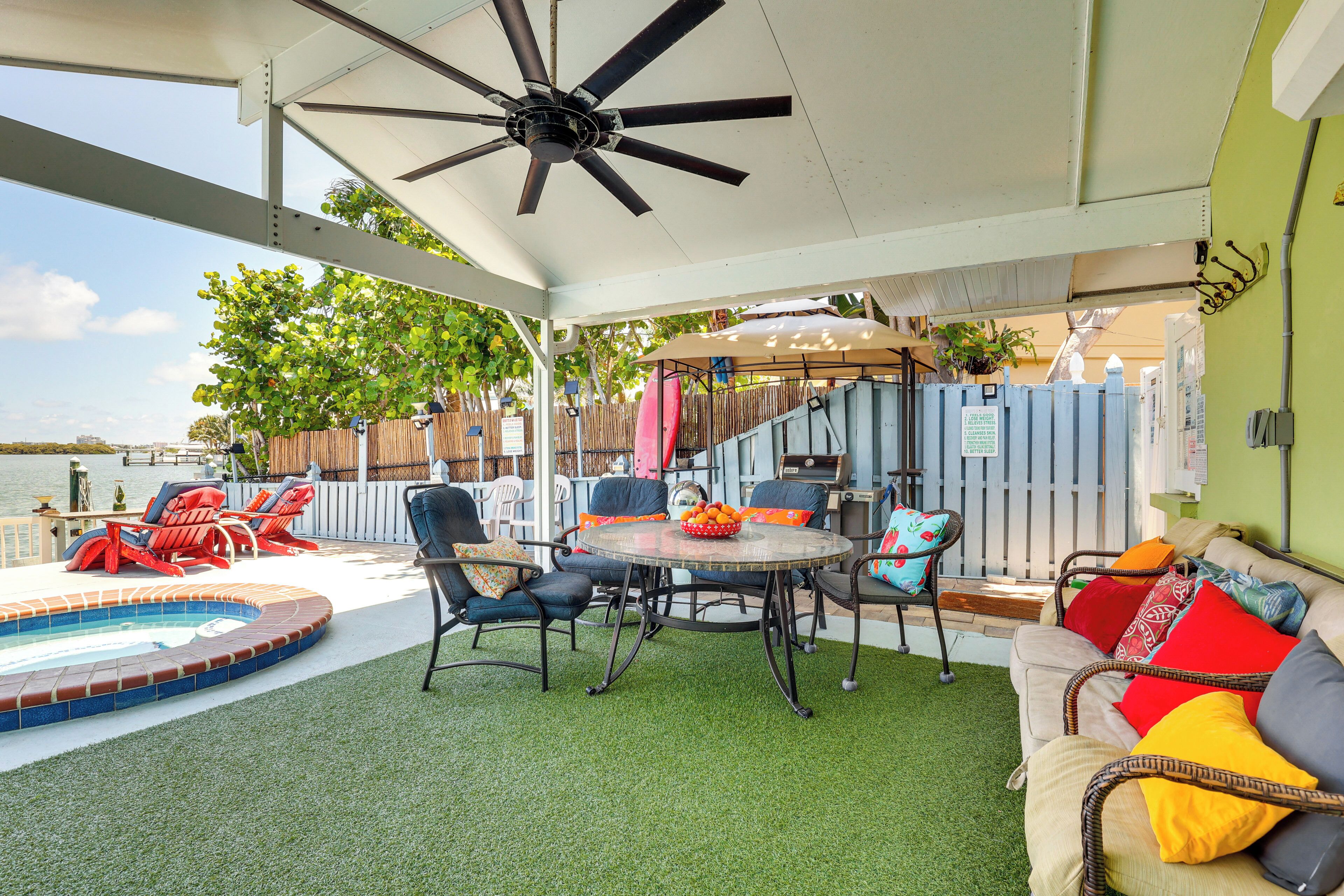 Un patio techado al aire libre con piscina, sillas de descanso y una mesa.