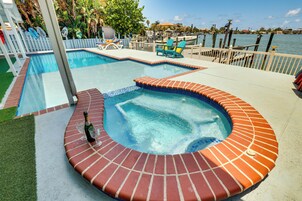 Una piscina con hidromasaje, rodeada por una terraza con sillas de descanso y vistas al agua.