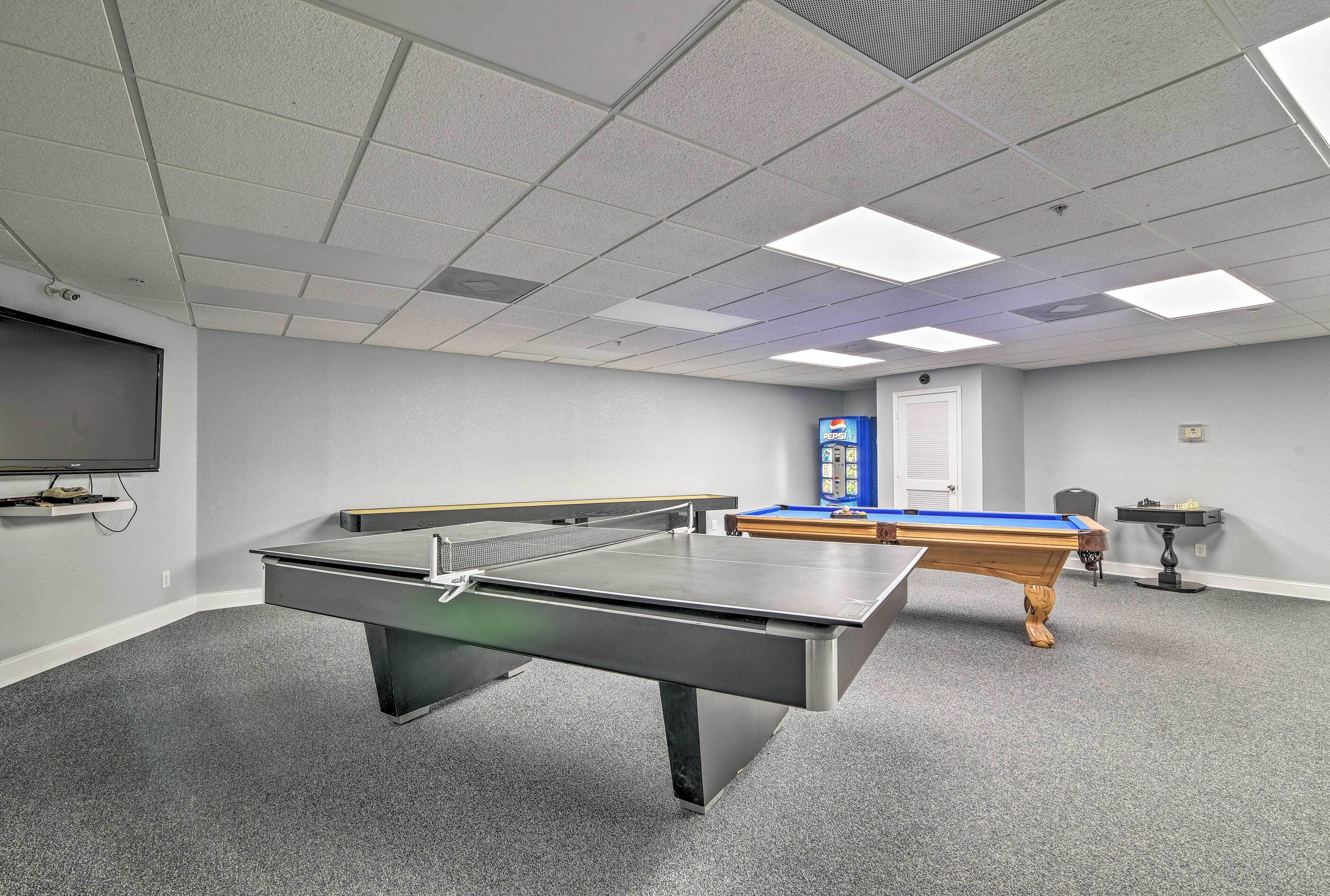 Une pièce équipée d’une table de billard, d’une table de ping-pong et d’un téléviseur fixé au mur.