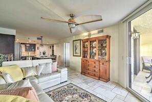 A spacious living room with a white sofa, a wooden cabinet, and a large window. - Gulf-view Hudson Condo in Waterfront Resort! (Hudson)
