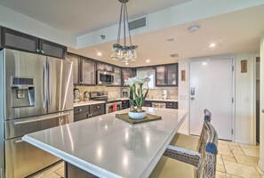 A modern kitchen with stainless steel appliances, a central island, and a chandelier. - Gulf-view Hudson Condo in Waterfront Resort! (Hudson)