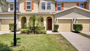 A two-story house with a beige exterior, a front entrance with a brown door, and two garages. - ~ 4 Mi to Disney: Compass Bay Resort Gem w/ Views (Kissimmee)