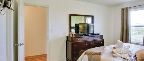 Una camera da letto con un letto, una cassettiera, una televisione e una finestra con tende.