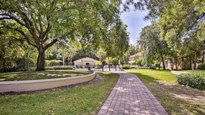 A paved pathway leading to a building with a red-tiled roof, surrounded by lush greenery and trees. - ~ 4 Mi to Disney: Compass Bay Resort Gem w/ Views (Kissimmee)