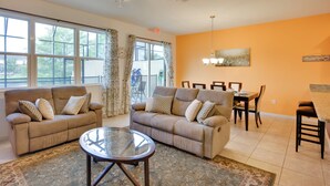 A living room with two sofas, a glass coffee table, and a dining area with a table and chairs. - ~ 4 Mi to Disney: Compass Bay Resort Gem w/ Views (Kissimmee)