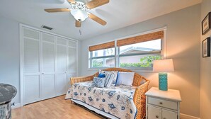 Une chambre à coucher avec un lit, une table de chevet, une lampe, un ventilateur de plafond et une fenêtre.
