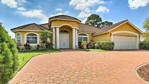 A two-story house with a brick driveway, a garage, and a well-maintained garden.