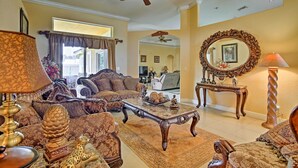A spacious living room with a large sofa set, a coffee table, and a ceiling fan.