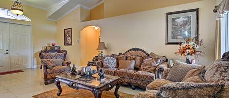 A spacious living room with a high ceiling, a large window, and a fireplace.