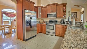 A kitchen with wooden cabinets, stainless steel appliances, granite countertops, and a dining area with a table and chairs.