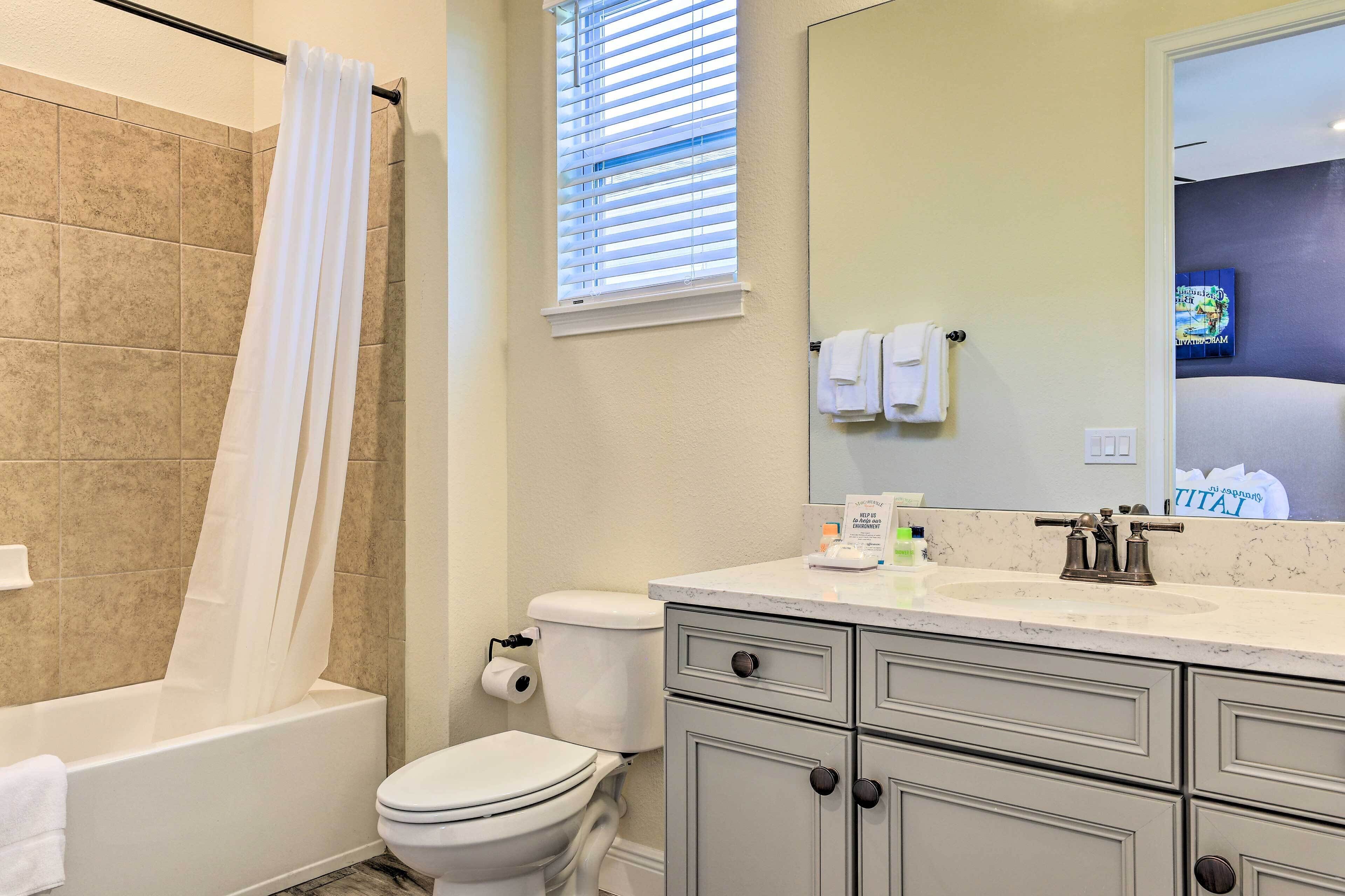 A bathroom with a bathtub, toilet, and vanity with drawers.