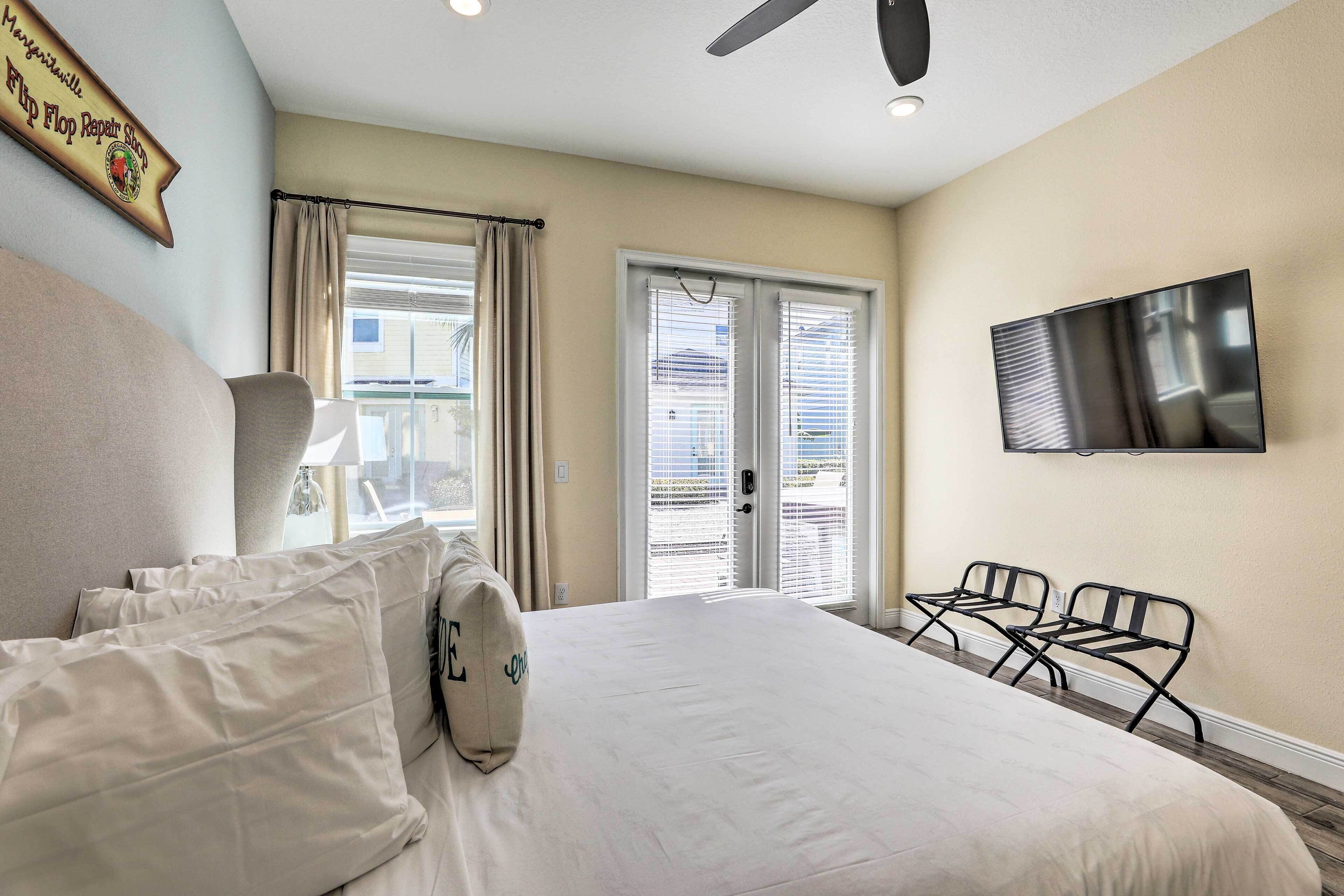 A hotel room with a bed, a TV mounted on the wall, and a seating area with chairs.