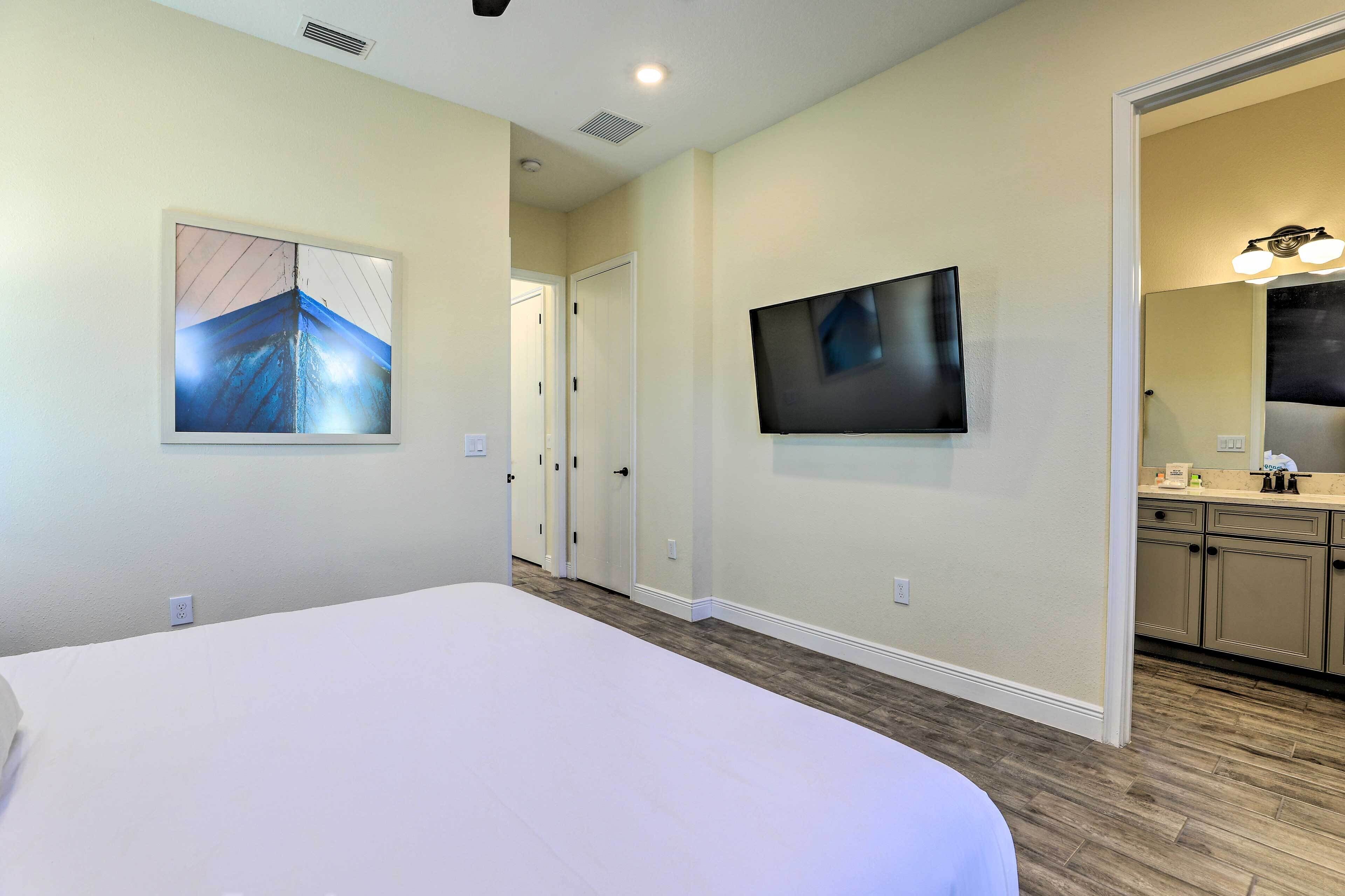 A hotel room with a large bed, a flat-screen TV mounted on the wall, and a painting on the wall.